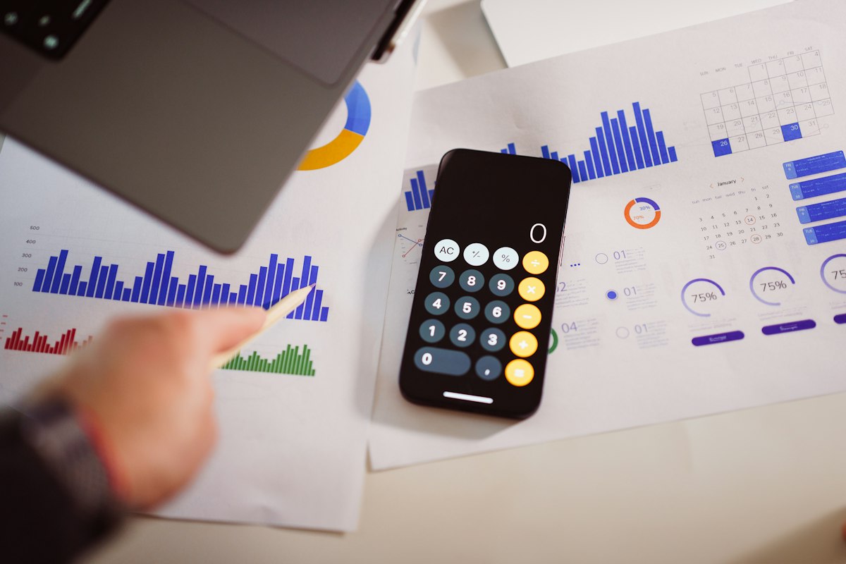 A calculator beside printed financial charts