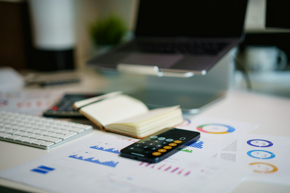 A desk with a phone, keyboard and financial charts