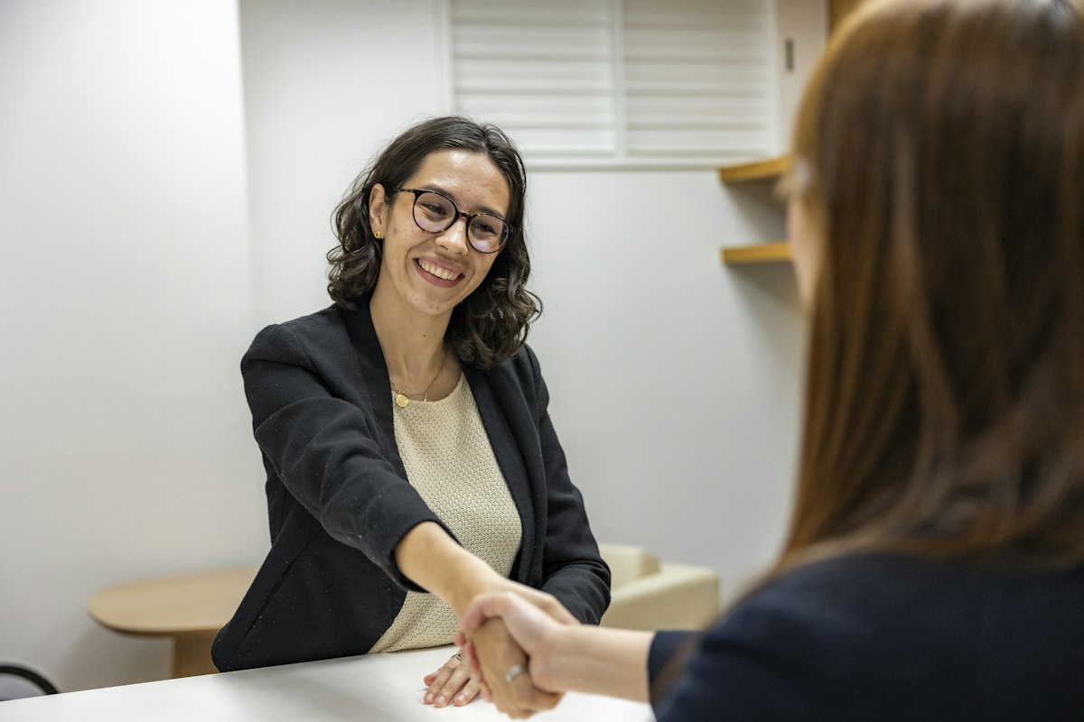 Two people shaking hands across a desk