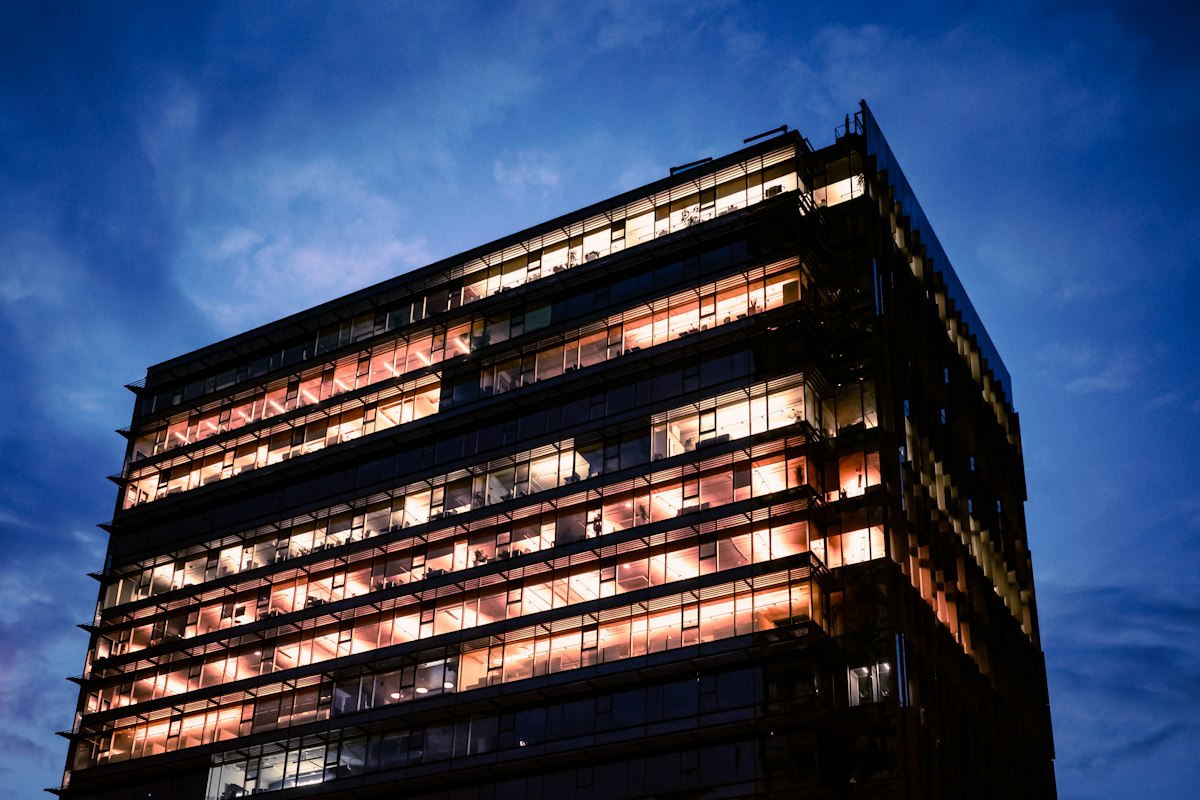 A modern office building with its windows lit at dusk