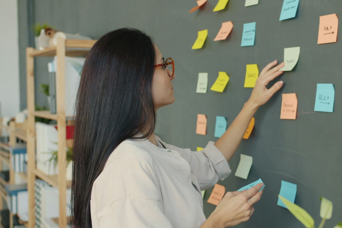 A project lead arranging tasks on a wall of sticky notes