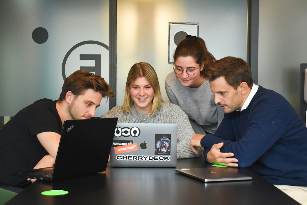 Four colleagues collaborating around a laptop